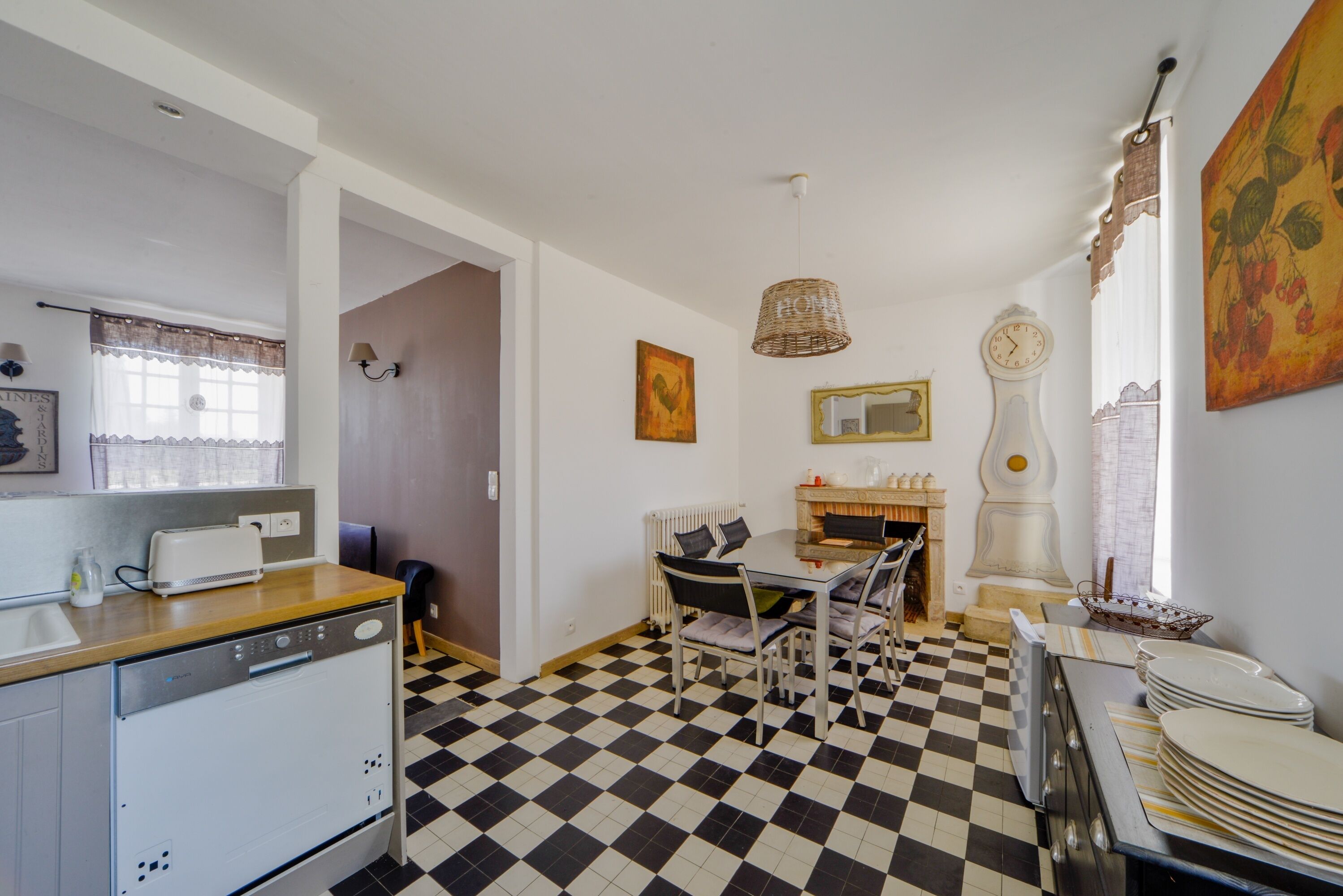 Una cucina compatta con pavimento a scacchi, un tavolo da pranzo con sedie, un frigorifero e un piano cottura.
