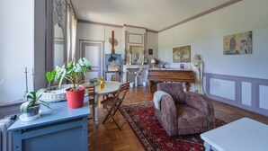 A spacious living area with a dining table, chairs, a sofa, and a red rug.