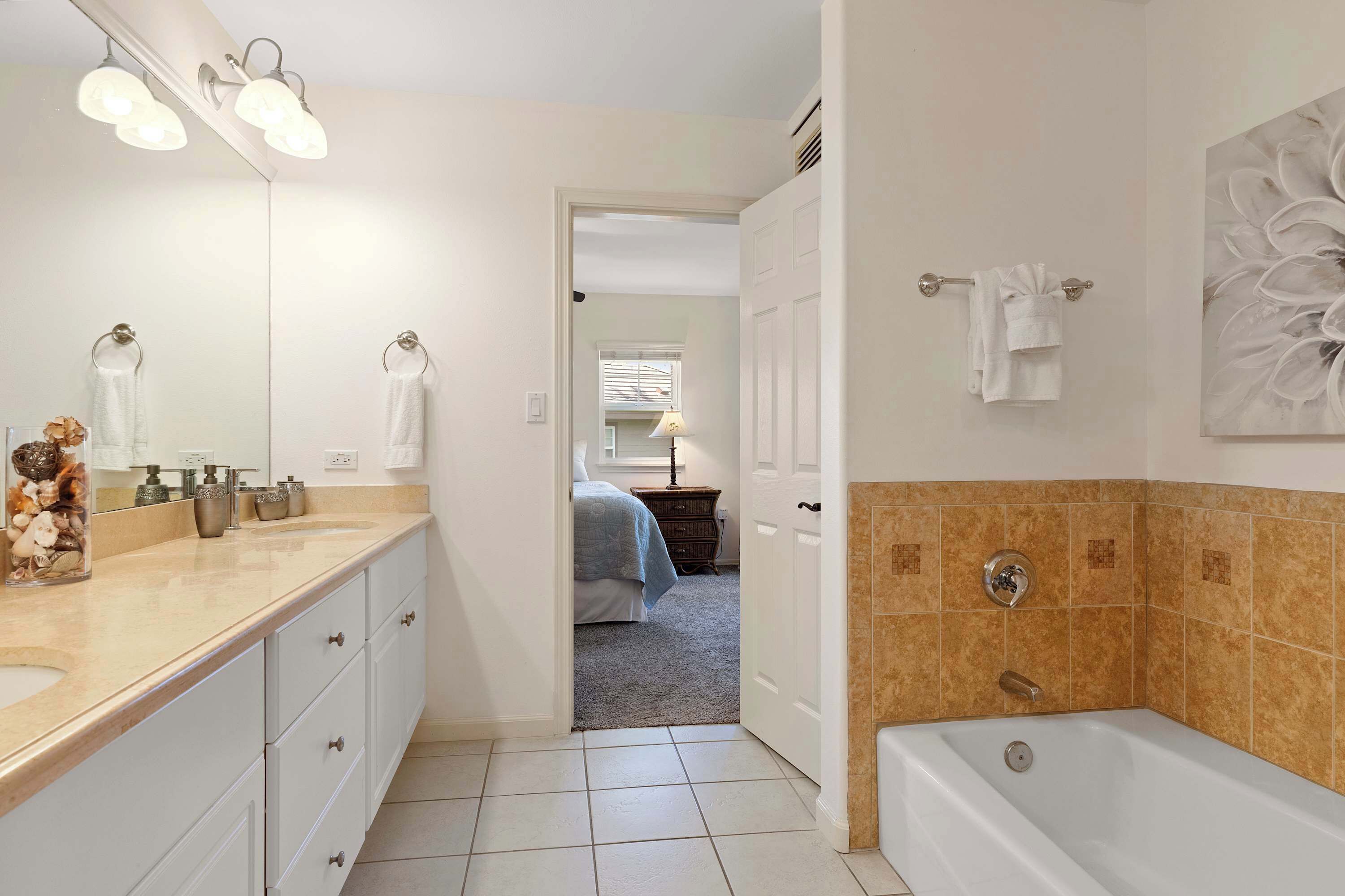 A bathroom with a double sink, a bathtub, and a large mirror.