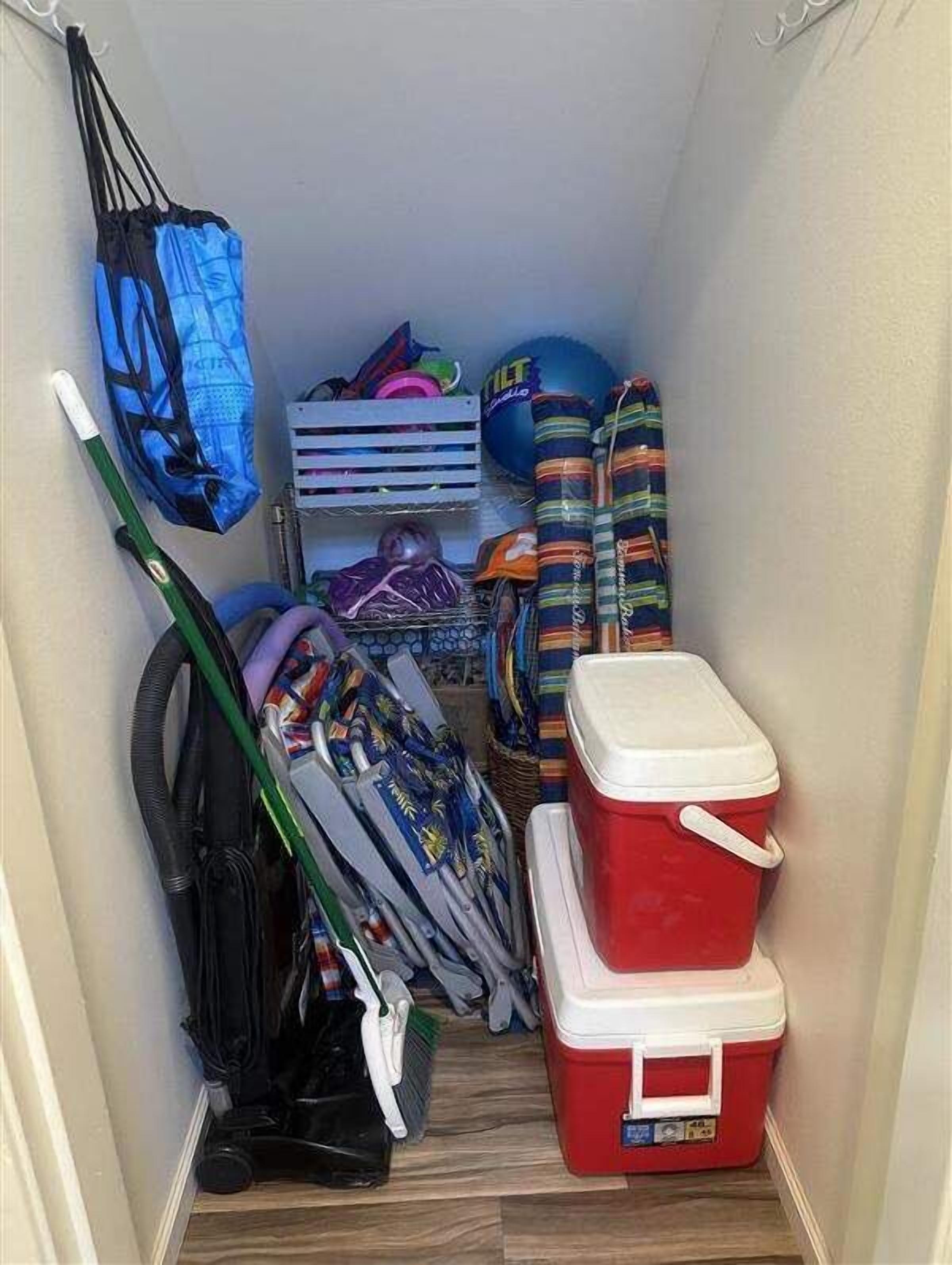 A narrow hallway with a red cooler, a blue bag, and various sports equipment.