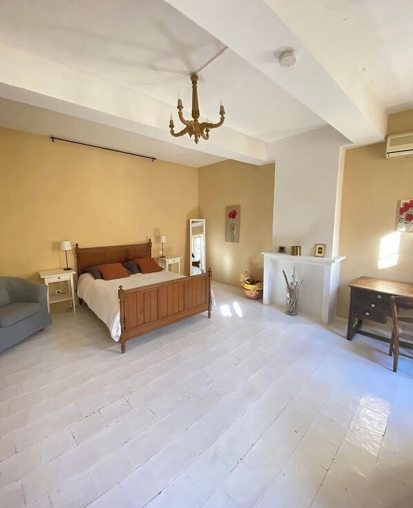 A spacious bedroom with a large bed, bedside tables, a desk, and a chandelier. - Logement Touristique Villa Eugénie (Lezignan-Corbieres)