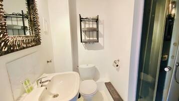 A bathroom with a white sink, toilet, and shower.