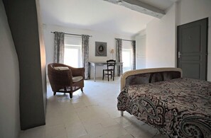 A bedroom with a bed, a chair, a desk, and a door. - Logement Touristique Villa Eugénie (Lezignan-Corbieres)