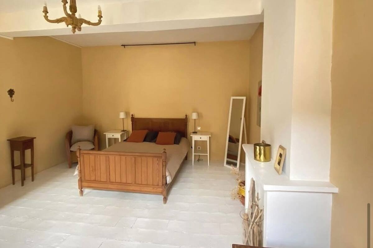 A bedroom with a bed, bedside tables, a mirror, and a dresser.