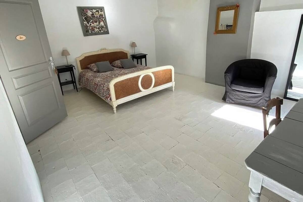 A bedroom with a bed, bedside tables, a chair, a mirror, and a door.