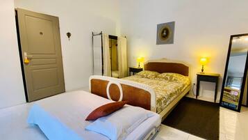 Hotelkamer met een bed, twee bedlampen, een deur, een spiegel en een aan de muur hangend schilderij.