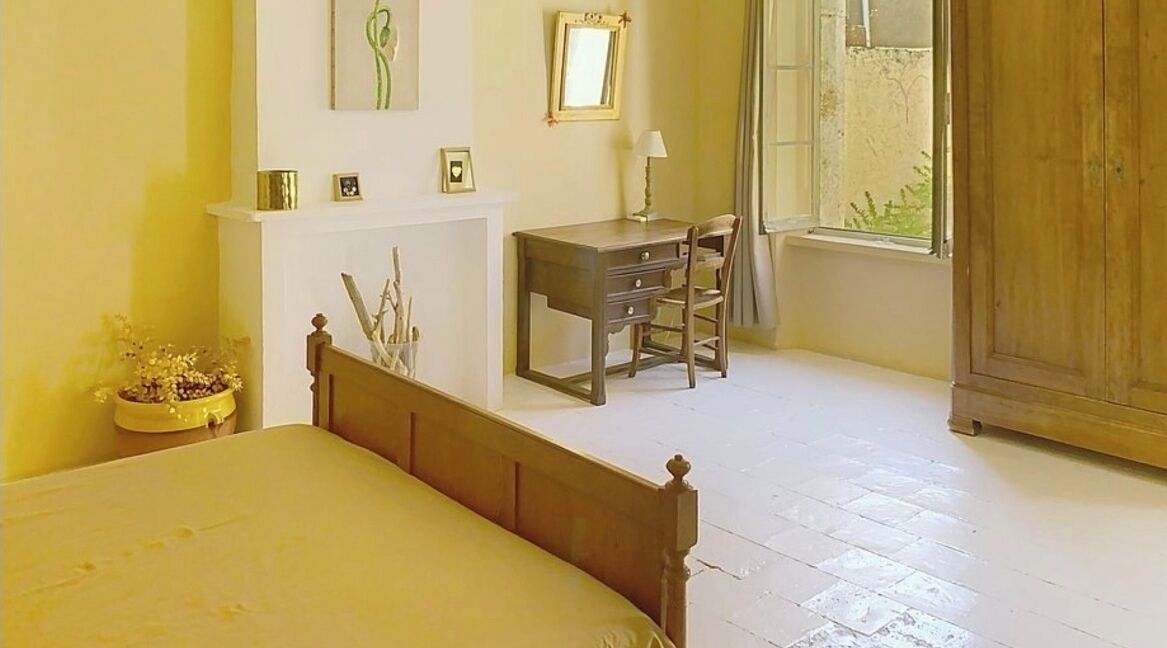 A bedroom with a bed, a desk, a chair, a window, and a wardrobe.