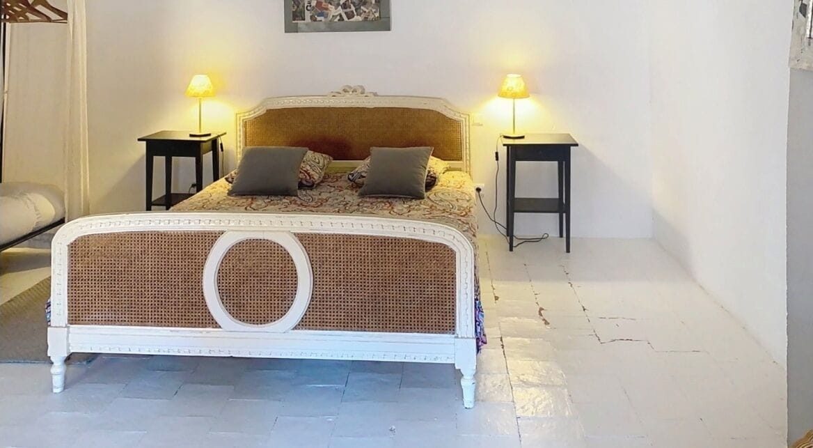 Une chambre à coucher avec un lit blanc, deux tables de chevet avec des lampes et une tête de lit.
