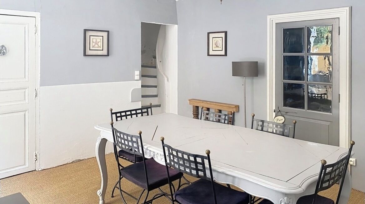 Ein Esszimmer mit weißem Tisch und Stühlen, gerahmten Bildern an den Wänden und einem Fenster mit Blick.