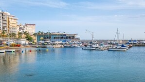 A marina with various boats docked, a building with a sign 'GIN', and a clear sky. - Alameda 16-2 Apartment Beach-Old Town (Benidorm)