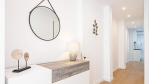 A modern interior with a white console table, a round mirror, and a minimalist lamp. - Alameda 16-2 Apartment Beach-Old Town (Benidorm)