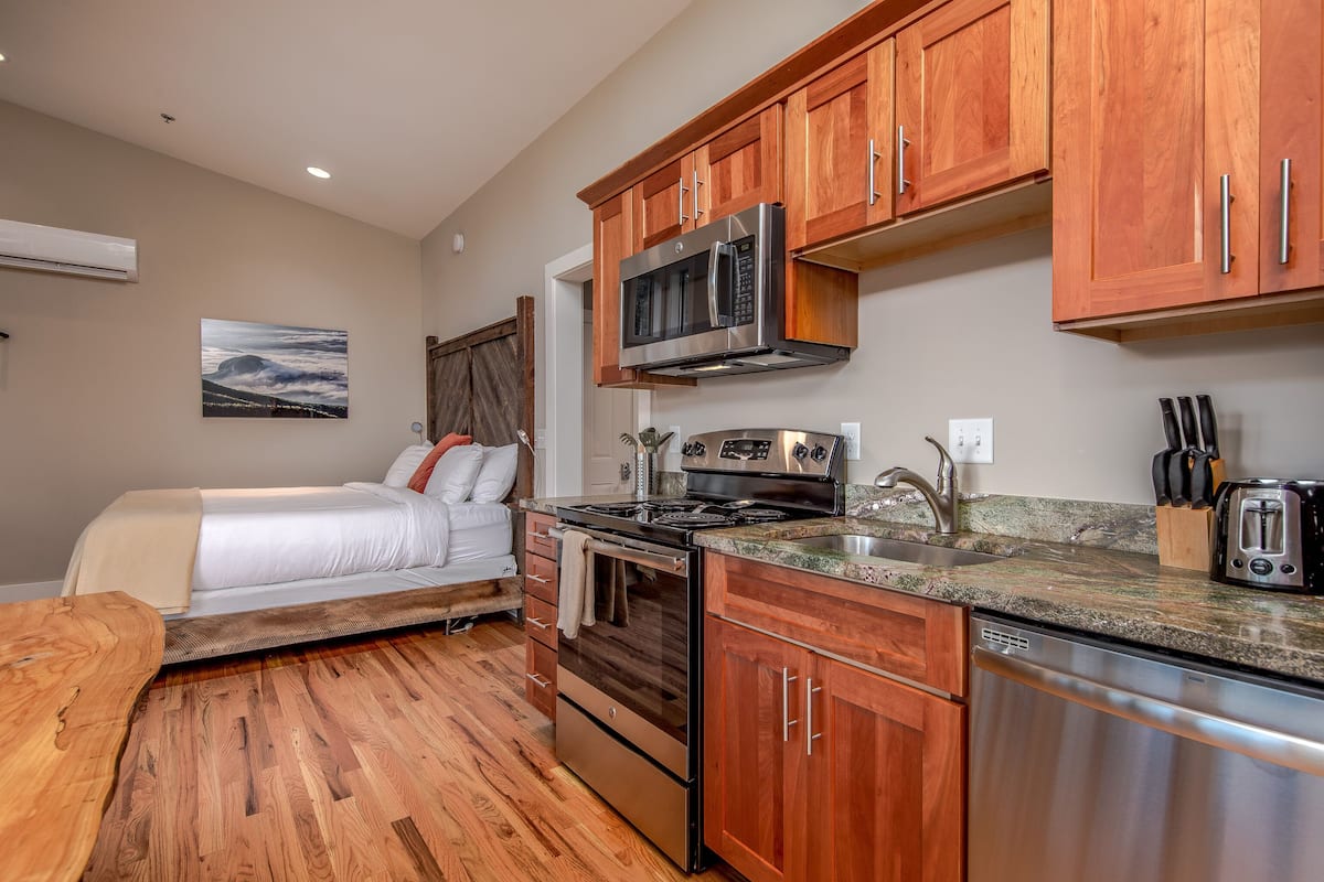 A compact kitchen with wooden cabinets, stainless steel appliances, and a granite countertop.