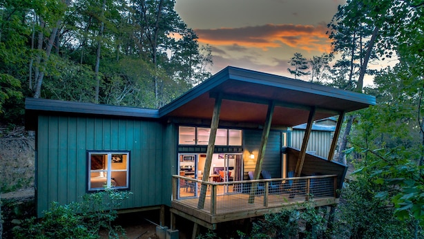 A modern house with a wooden deck, large windows, and a staircase leading to an upper level. - Pilot Cove Forest Lodging (Pisgah Forest)