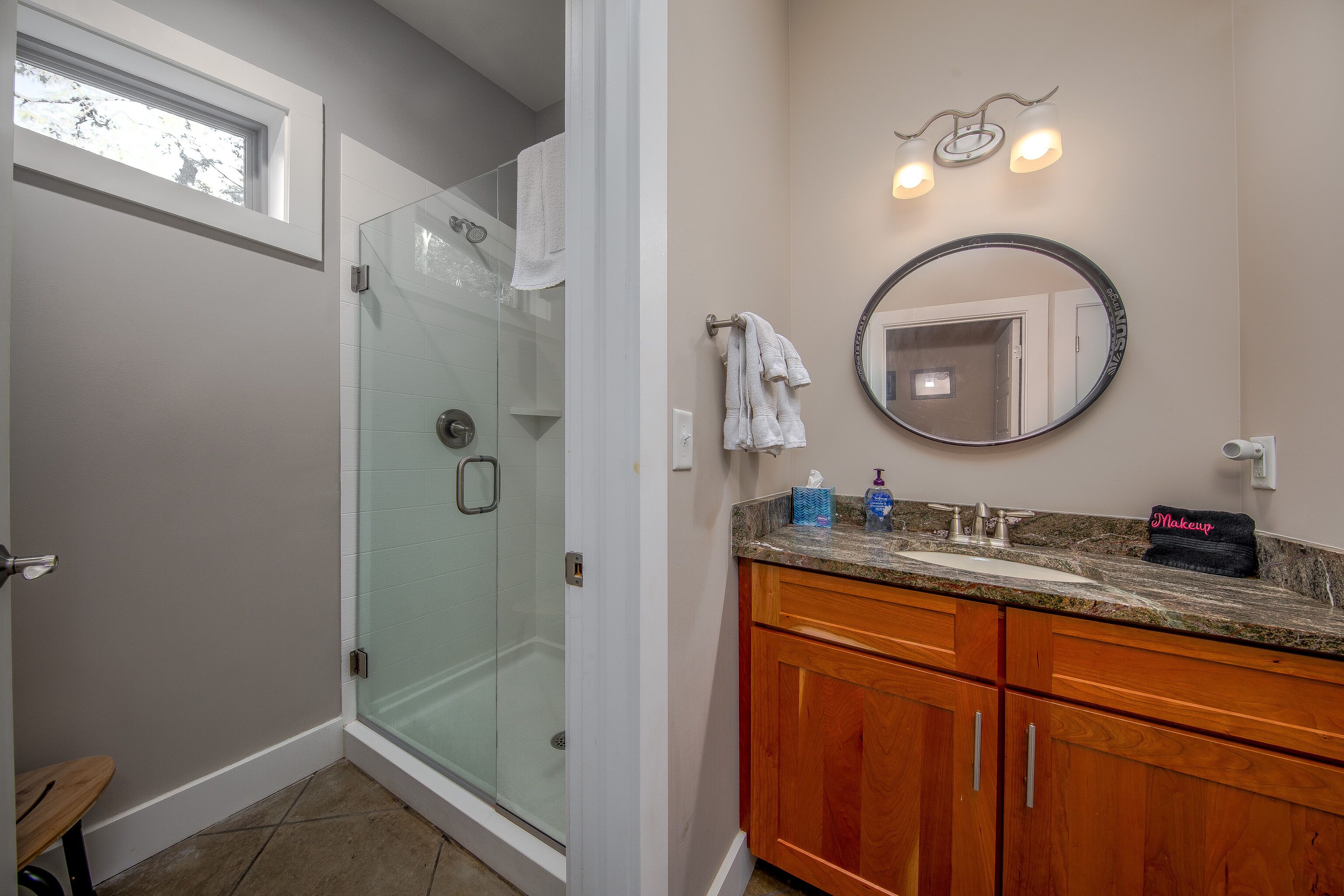A bathroom with a glass shower enclosure, a vanity with a sink, and a mirror.