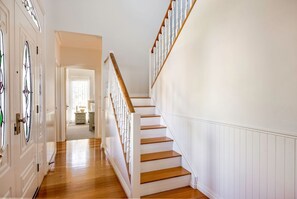 Eine Treppe mit weißen Geländern und Holzstufen, die zu einem Zimmer mit einem Fenster führt.