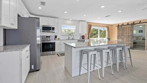 A modern kitchen with white cabinets, stainless steel appliances, and a large island with bar stools.