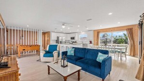 A modern living room with a sofa, coffee table, and a dining area with a table and chairs.