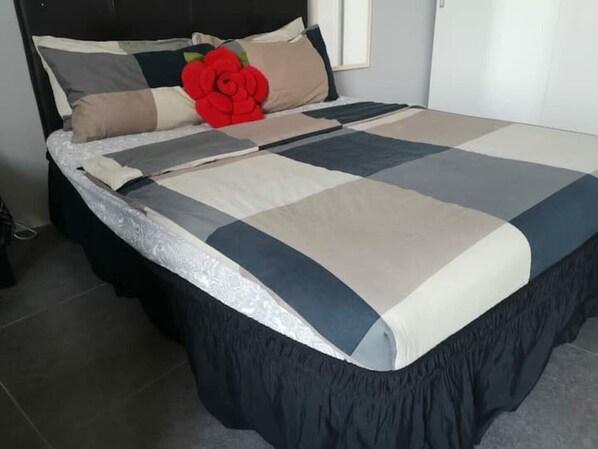Restful retreat with a geometric-patterned bedspread and a single rose.