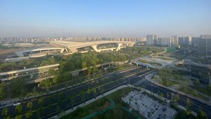 An aerial view of a modern urban area with a large, curved bridge structure, multiple roads, and surrounding high-rise buildings. - HengQI hotel (Hangzhou)