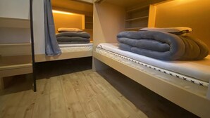 A dormitory-style room with bunk beds, wooden flooring, and a warm ambient light. - HengQI hotel (Hangzhou)