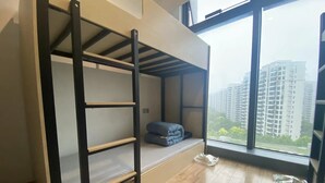 A bunk bed room with a view of high-rise buildings. - HengQI hotel (Hangzhou)