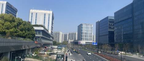 A modern urban street with high-rise buildings, a pedestrian crossing, and a clear sky.