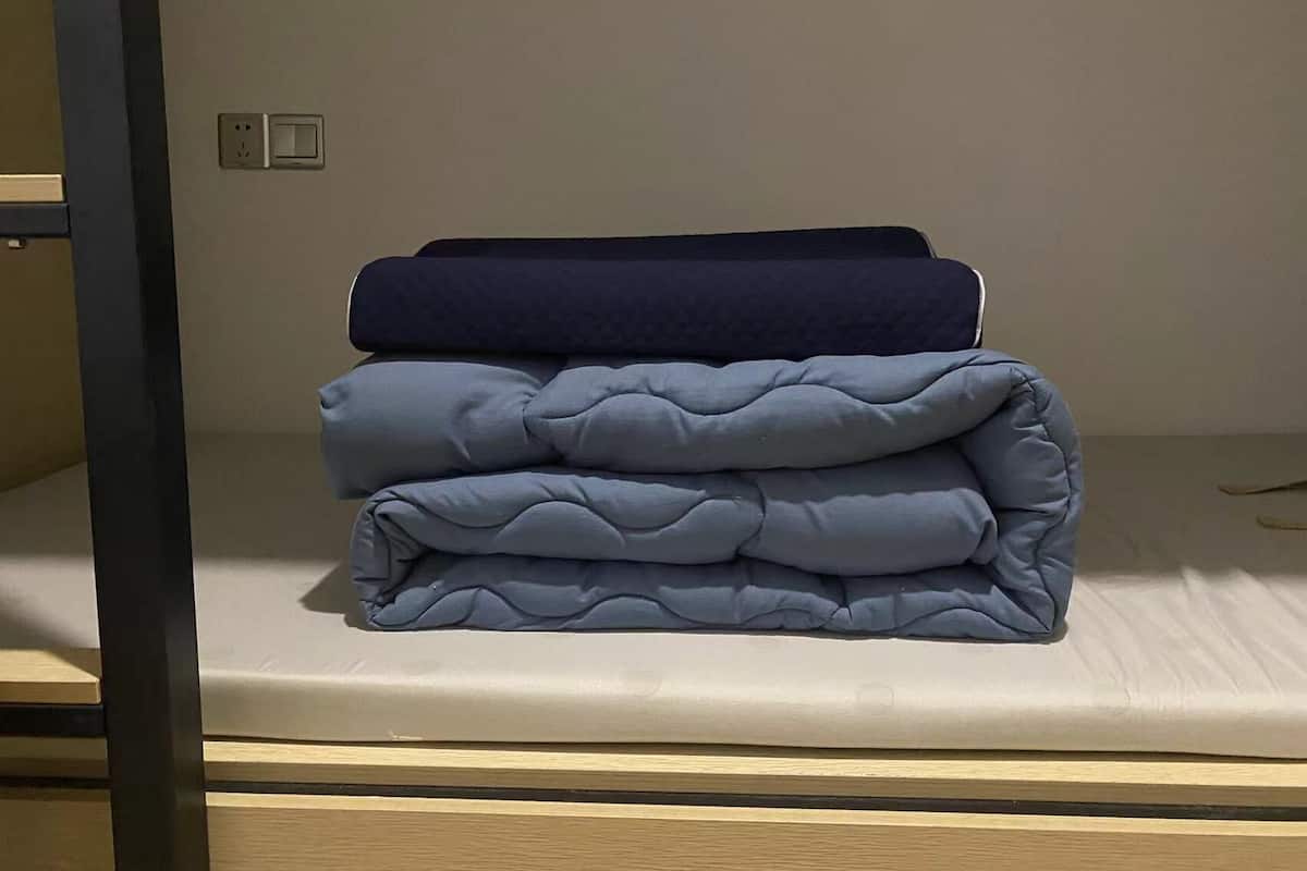 A bunk bed with a mattress and a folded blanket.