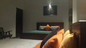 A bedroom with a bed, pillows, a chair, and a wall-mounted TV.