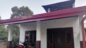 A building with a covered porch, two wooden doors, and a parked motorcycle.