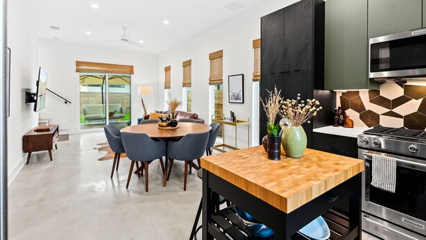 A modern kitchen with a built-in microwave, stove, and dining area with chairs and a table. - Stylish 2 Bedroom Retreat in South Austin (Austin)