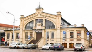A historic building with a large arched entrance, a clock, and a sign reading "HALES TURGUS". - Luxury apartments 3 (Vilnius)