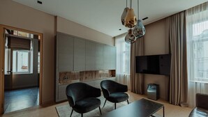 A modern living room with a sofa, two armchairs, a coffee table, and a TV mounted on the wall. - Luxury apartments 3 (Vilnius)