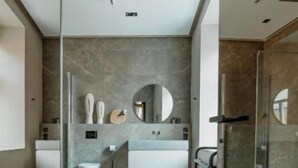 A modern bathroom with a large mirror, a bathtub, and a shower area. - Luxury apartments 3 (Vilnius)