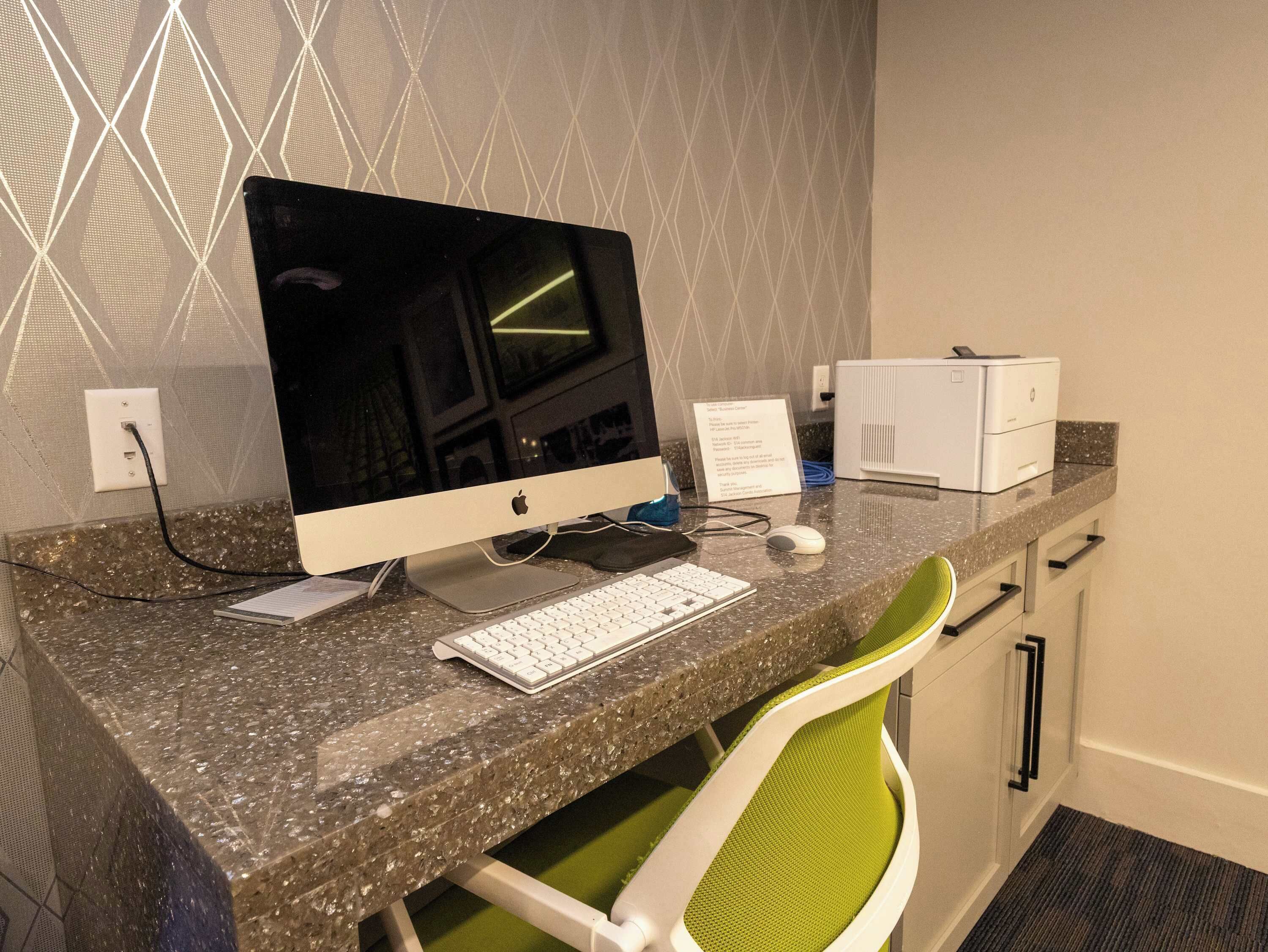 Ein Hotelarbeitsplatz mit Schreibtischcomputer, Tastatur, Maus und Drucker auf einer Granit-Arbeitsplatte.