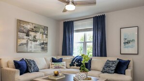 A living room with a beige sectional sofa, a wooden coffee table, and a large abstract painting on the wall.