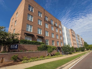 A multi-story brick building with a number '514' sign, a sidewalk, and a clear sky.