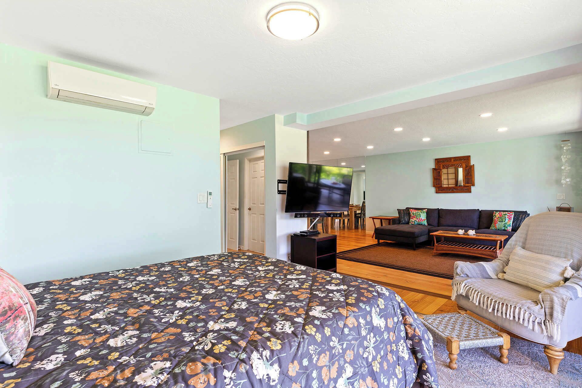 A bedroom with a bed, a TV, a sofa, and a dining area.