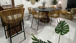 A dining area with a round table, wicker chairs, and a potted plant.