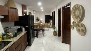 A modern kitchen with a dining area, marble flooring, and decorative wall art.