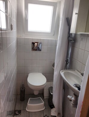 A small bathroom with a toilet, a sink, and a window above the toilet. - Acropolis penthouse with breathtaking city view (Athina)