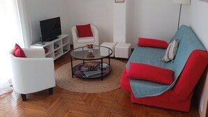 A living room with a sofa, armchair, coffee table, and a television on a stand. - Acropolis penthouse with breathtaking city view (Athina)