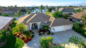 A residential area with a house featuring a tiled roof, a front porch, and a driveway. - Luxury Tropical long waterfront view w/bikes,kayaks,golf clubs,beach gear incl. (Punta Gorda)
