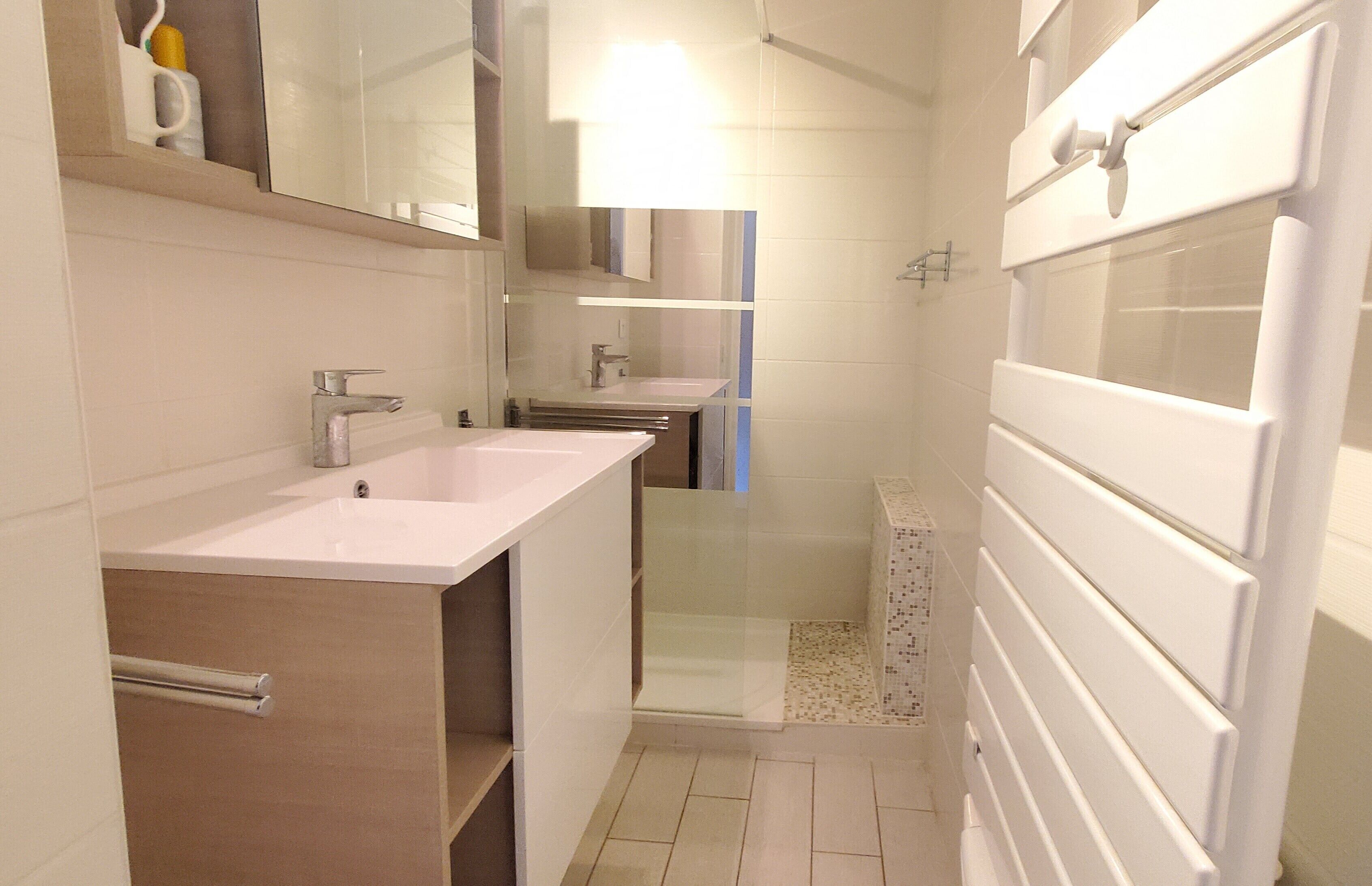 A modern bathroom with two sinks, a glass shower enclosure, and a large mirror.