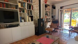 Un soggiorno con televisione, scaffali, camino e tavolino in vetro.