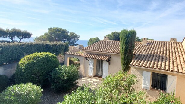 Una villa in stile mediterraneo con tetti in tegole di terracotta, immersa nel verde e con vista sul mare.