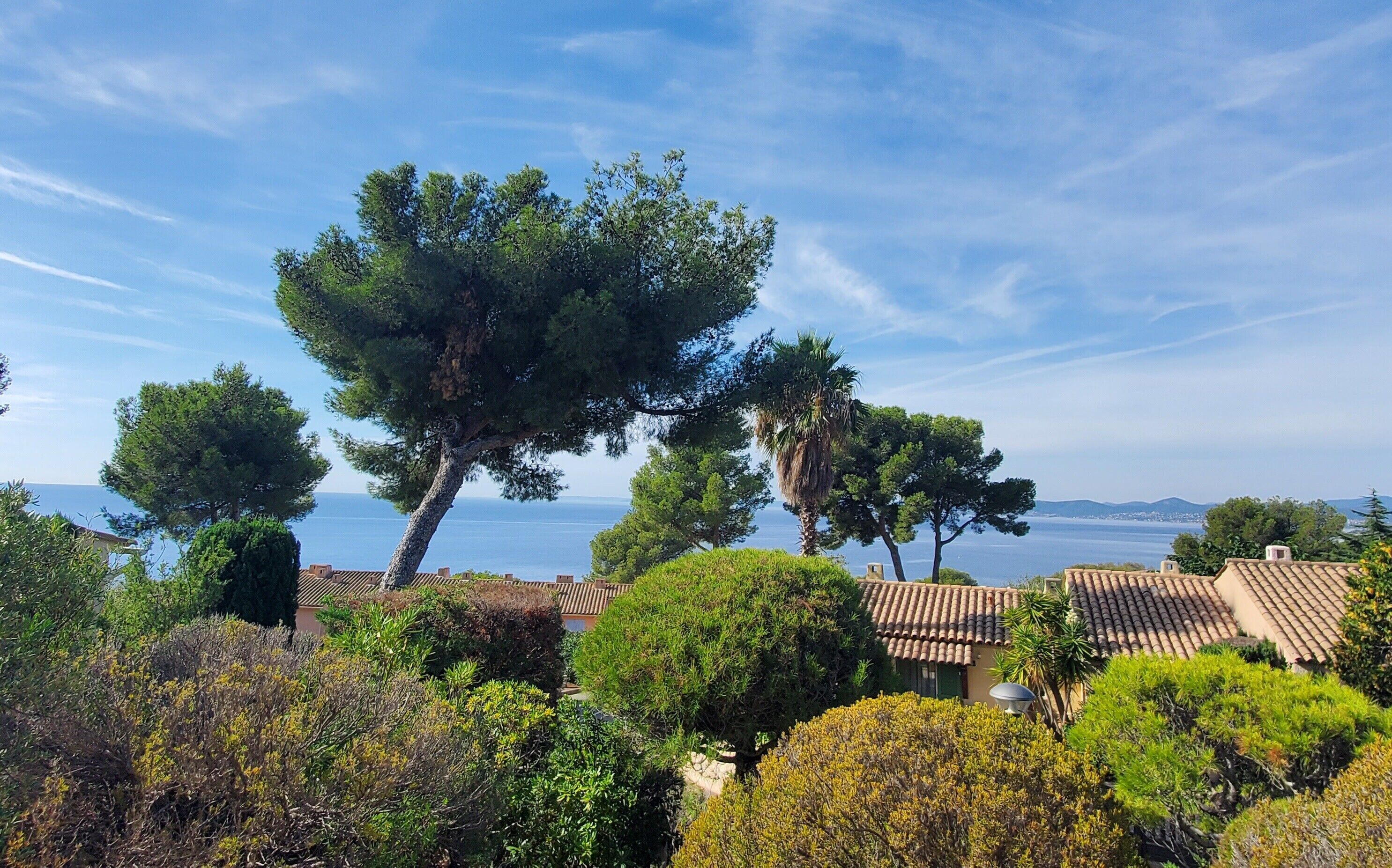 Eine Küstenvilla im mediterranen Stil, umgeben von üppiger Vegetation mit Blick auf das Meer.