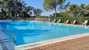 Una piscina rettangolare con una scala metallica a sinistra, circondata da un solarium in mattoni.