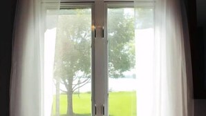 A room with a large window featuring a view of a tree and a green field. - Entire 3 Bedroom Lake House in Beaver Dam (Beaver Dam)