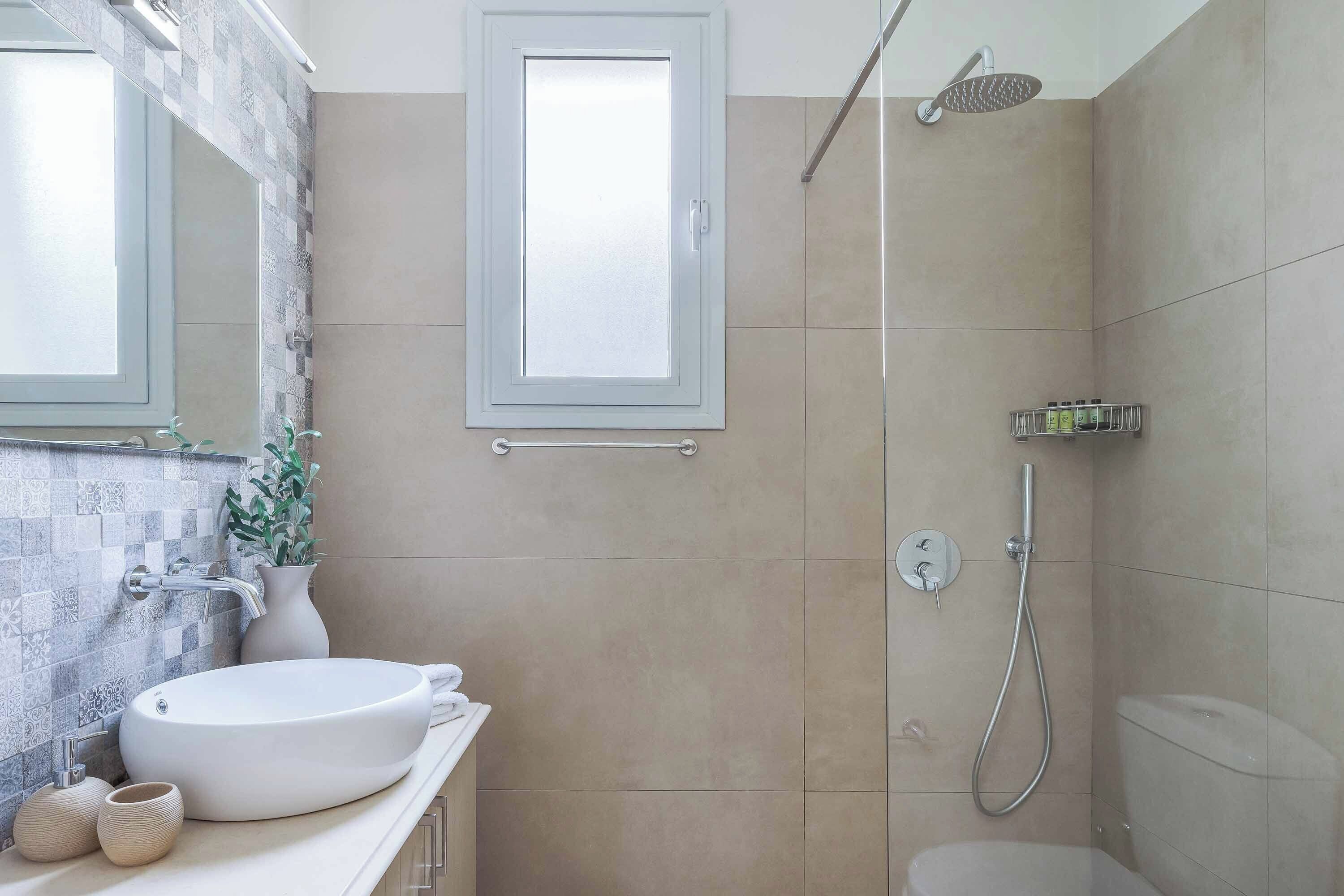 A bathroom with a large sink, a shower, and a window.
