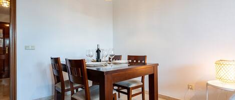A dining area with a wooden table, four chairs, and a hanging light fixture.